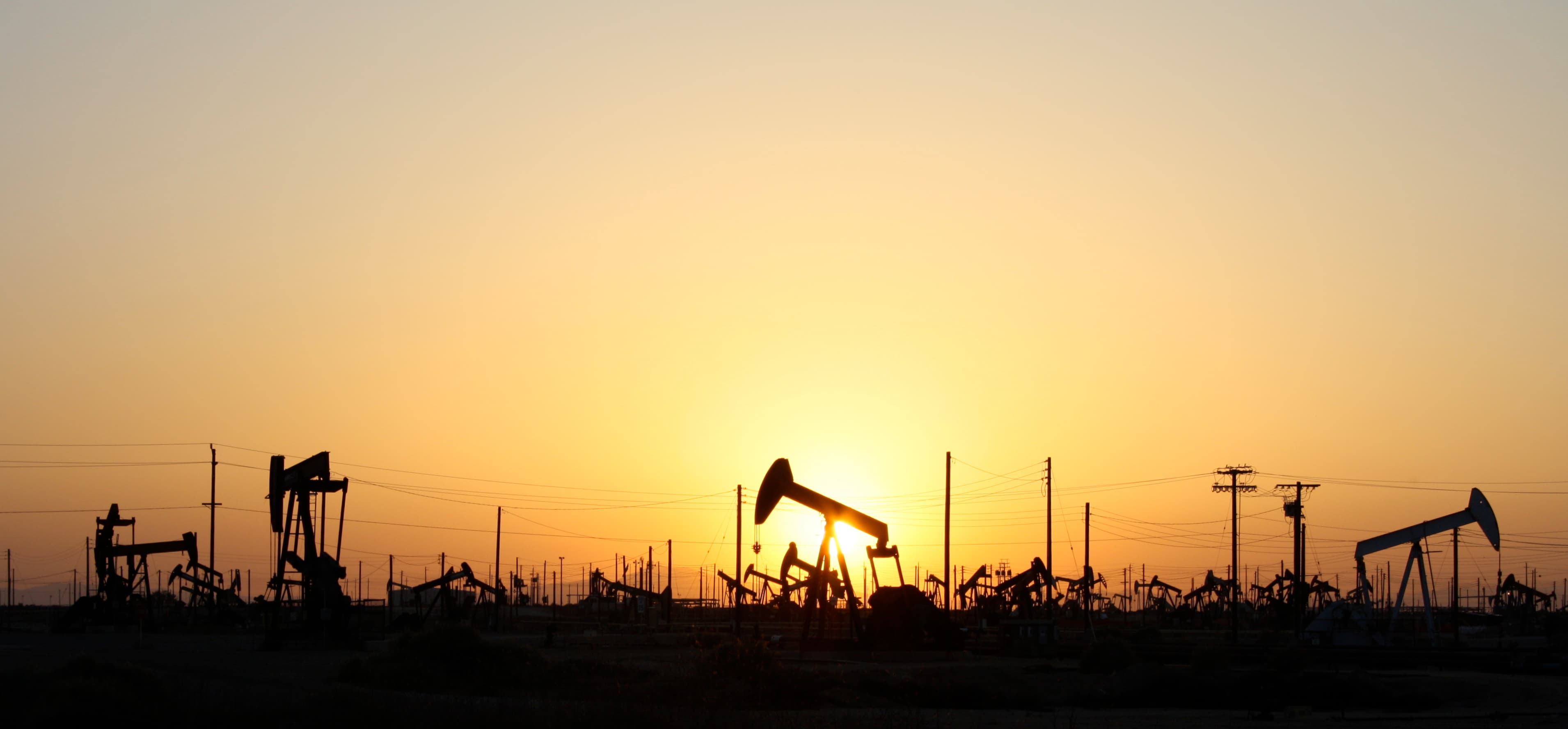 Oil-field pumpjacks silhouetted against a sunset